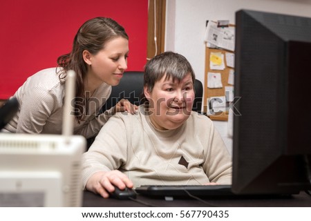 caregiver and mentally disabled woman learning at the computer, special education