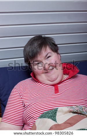 a sitting mentally disabled woman reads and smiles