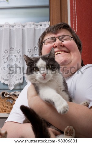 a sitting mentally disabled woman is holding a cat