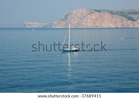 The yacht is moving across the sea with mountains on background