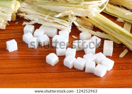 Many white sugar cubes and sugar cane
