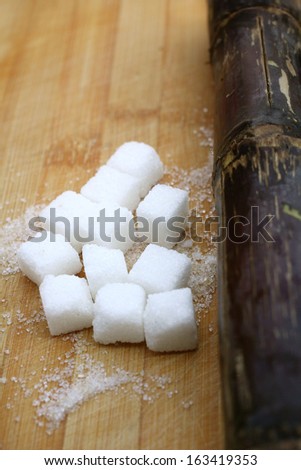 White sugar cubes and red sugar cane