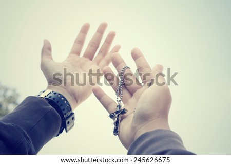 Hands reaching with cross