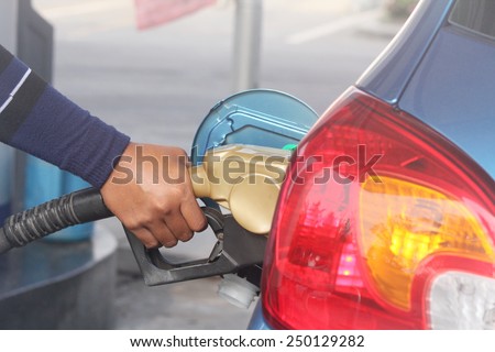 Hand refilling the car with fuel.