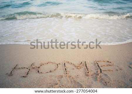The word home written in sand on beach