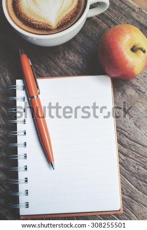 Blank notepad and apple with latte art coffee on office table