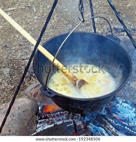 black pot on camp fire, cooking in big metallic cauldron outdoor