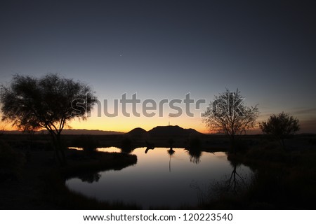 Clear yellow, pink and blue dawn sky and water reflection in Autumn over rural pond/Clear Colorful Twilight Sky over Water in Rural Landscape /Cloudless sunup sky and water reflection in Fall season