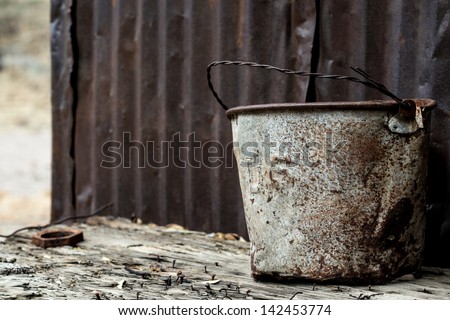 The letters, US, on a rusting bucket with  twisted wire handle near the early 1900s homestead of Faraway Ranch in the Chiricahua National Monument/Letters, US, on 1900s Bucket Outdoors/An old US pail