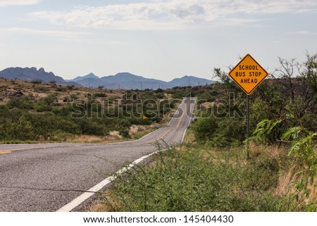 School Bus Stop Ahead sign along paved two-lane country road  in southeastern Arizona/Rural Road Landscape With School Bus Stop Sign/Road sign in countryside scenery about school bus stop ahead