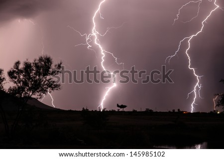 Cloud to ground lightning in Arizona, USA, during summer monsoon season/Weather Vane Silhouette during Nighttime Lightning Strikes in Summer Monsoon Season/Thunderstorm lightning strikes in desert