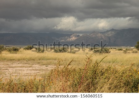 Layers of heavy gray clouds and light over mountain range and semi-desert grass landscape in Autumn/Cloud Layers over Desert Landscape/Cloudscape with layers of gray clouds over mountains and prairie