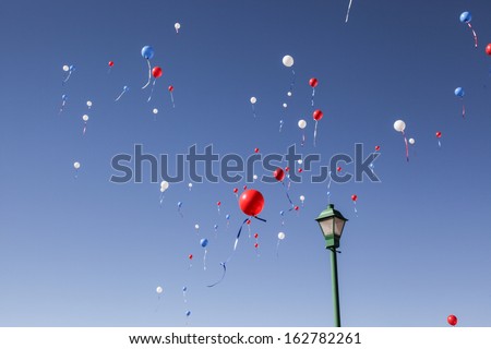 Red, white, blue balloons float in clear blue sky/Balloons in Red, White, Blue float in Clear Daytime Sky/Balloons in red, white and blue colors in blue sky