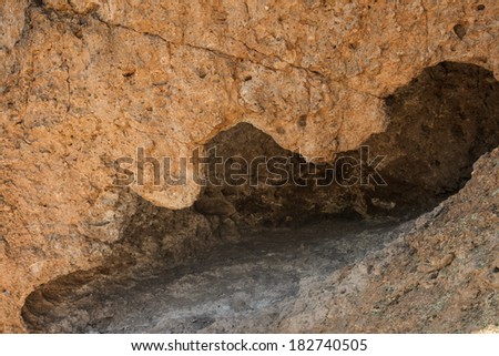 Cave of dacite lava flow with shady interior in southwestern United States of America/Rocky Abode/Narrow opening with jagged edge to a cave in Coronado National Forest of Arizona, USA