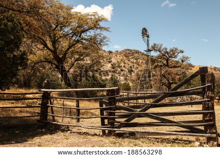Windmill and old wooden gates at livestock ranch in semi-desert area/Vintage Wooden Entrance and Windmill at 1900s Ranch in Semi-desert Scenic/Old windmill with gates and fence in rural high desert