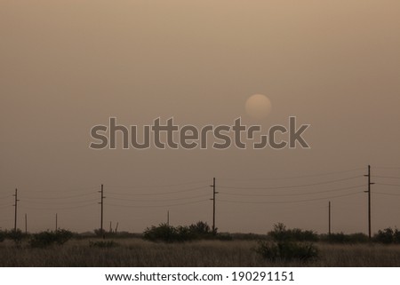 Countryside enveloped in dust at sunset in semi-desert area/Dust Pollution Masks Setting Sun/Setting sun in thick cover of dust in desert Southwest USA