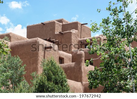Large building with typical brown color walls and architecture in Santa Fe, New Mexico, USA/Santa Fe, New Mexico, Architectural Style/Tall and big adobe-type structure on sunny day