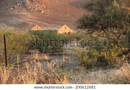 Roofless old and empty homestead with rock walls in semi-desert environment/Vintage Empty and Roofless Stone Homestead in Semi-Desert Landscape/Roofless old home built with rocks in rural countryside
