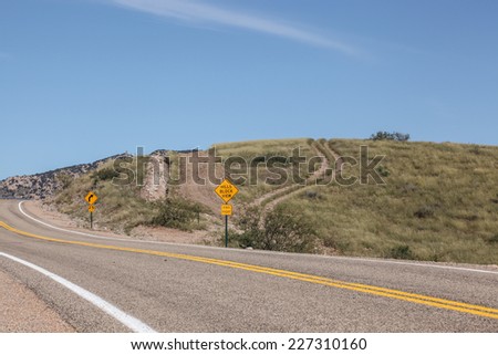 Hilly, curving USA two lane paved highway and sign warning HILLS BLOCK VIEW..Stay Right/Winding USA Paved Road in Hilly Scene with Sign Warning that HILLS BLOCK VIEW..STAY RIGHT/Hills road and signs