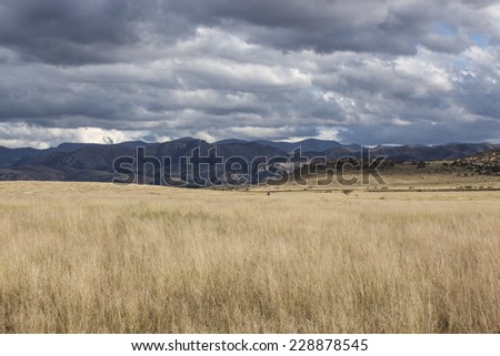 Autumn scenic of dry grasslands, mountains and cloudy sky/Landscape of Mountains and semi-desert Grasslands with Stratocumulus Clouds across Sky during Autumn/Mountains, prairie and Fall cloudy sky