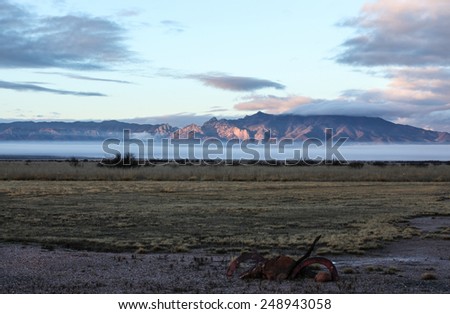 Semi-desert landscape with ground fog at sunlit mountains in winter morning/Pink Sunlight on Mountains with Baseline Ground Fog in Weather Landscape/Pink sunshine on mountains with low fog in winter