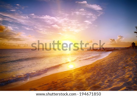 Beautiful sunset over the sea with a view at stony shore on the white beach on a Caribbean island of Barbados