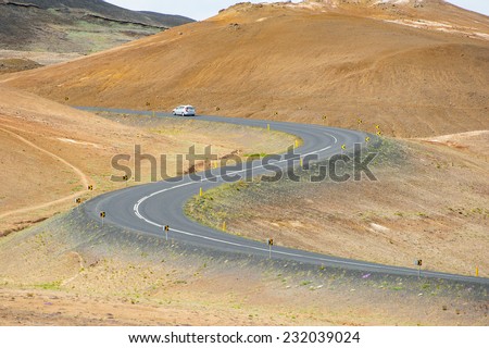 Road with cars leading through the mountain landscape looks like a big symmetric S letter, Iceland.