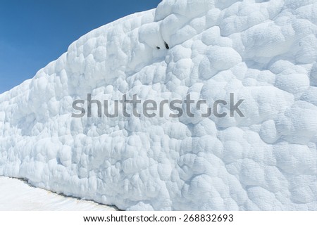 Pamukkale (cotton castle) natural wonder is created by a layers of white travertine looking like cotton, Turkey. Natural pamukkale wall against a blue sky