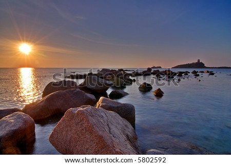 Sunrise in Sardinia with lighthouse and stone pier