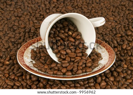 A lot of coffee beans are scattered from the cup