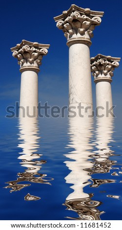Three ancient greek pillars against a blue sky  reflecting in water