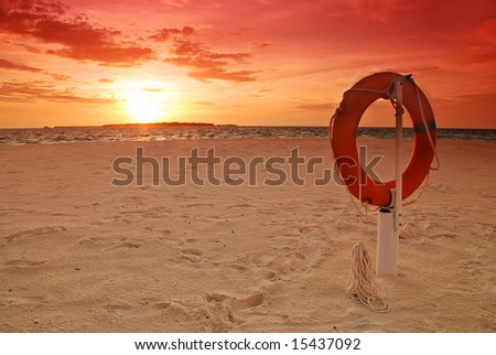 Sunset over the ocean and lifebuoy on the beach