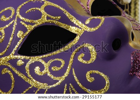 Detail of a beautiful Venetian mask with a half from gold and a half from violet on a black background