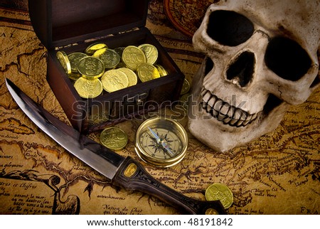 Pirate treasure. Old brass compass lying on a very old map with treasure chest full of golden coins, skull and knife