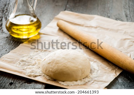 wooden rolling pin with freshly prepared dough for pizza and dusting of flour