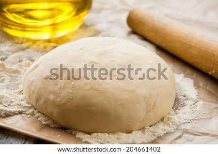 wooden rolling pin with freshly prepared dough for pizza and dusting of flour