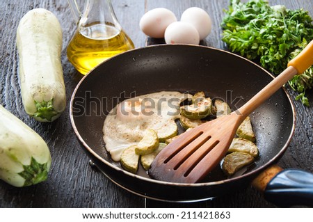 fried eggs with zucchini and parsley on the pan
