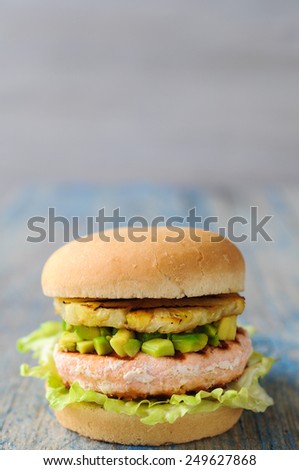 Homemade fish burger with salmon, avocado and pineapple.Close up