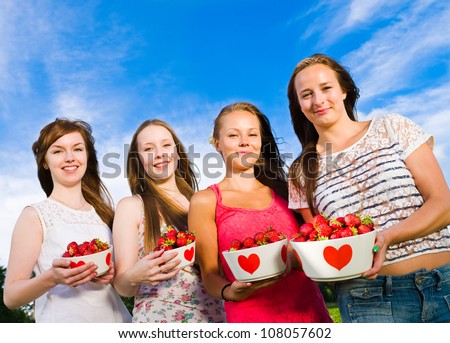 Group of girls smiling and they have full bowl of a strawberries, blue sky on the background, horizontal format