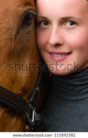 Woman and horse together, woman looks toward camera, vertical format