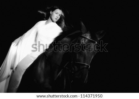Beautiful woman dressed in white costume riding a horse, black and white image