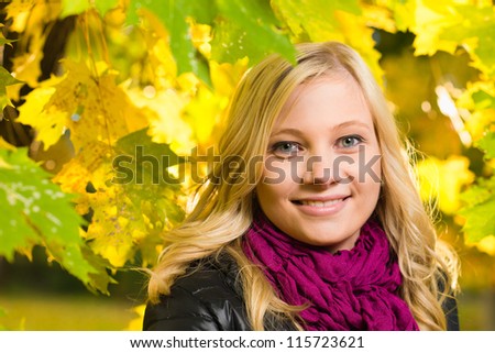 Beautiful girl face poses on a park, autumn color leaves on the background, horizon format