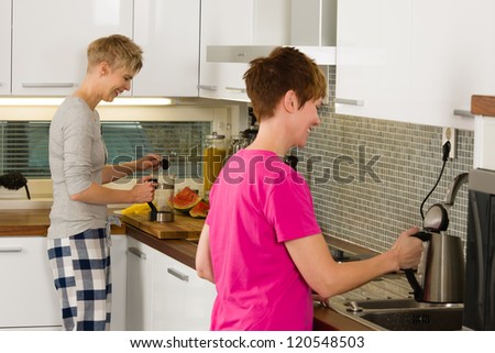 Happy lesbian couple making coffee in the kitchen, vertical format