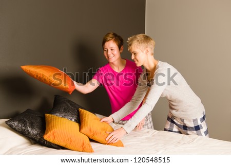 Lesbian couple make the bed in the morning, horizon format