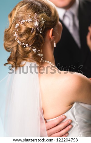 Bride have a beautiful decoration on a hair, groom on background, vertical format