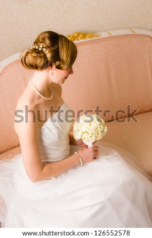 Beautiful bride holds a bridal bouquet, focus on wedding hairstyle