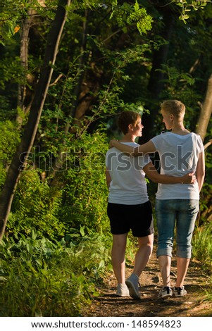 Lovely lesbian couple walks together in forest, evening