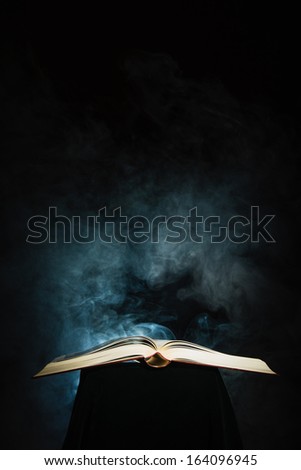 Opened big book and smoke, dark background, vertical format