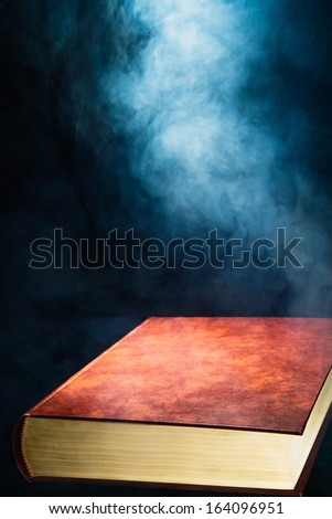 Floating unopened book and smoke, dark background, close up