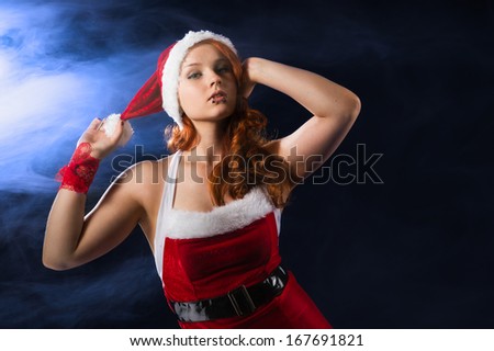 Attractive girl wearing on Santa Claus costume, waist up composition, smoke and dark blue background